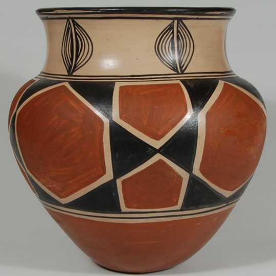 In this jar, the artisan used a combination of the Black-on-cream style and the black and red style she had developed. The combination of the two styles is rather unusual and enormously striking. She decorated the neck with simple black lines expanding outward from black parallel lines over a cream background.  The mid-body of the vessel features strong brick-red geometric elements, outlined by a cream background and separated by black geometric elements.  The lower body is traditional brick-red coloration. The underbody is slightly concave.