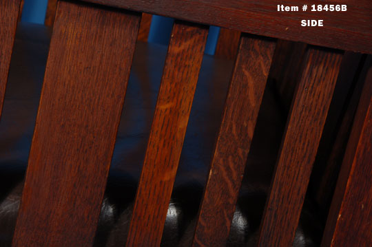 The chair and rocking chair (pair) are low and square with one wide slat in the center of the back, flanked by three thinner slats on each side.  The side panels under the armrests are of the same style.  The seat cushions are removable and have been recovered with dark brown faux leather.  The chairs date to the early 20th century.  Condition:  The chairs are in excellent condition with the original finish showing normal wear.  Provenance: Purchased in 1991 from a New England antiques dealer 