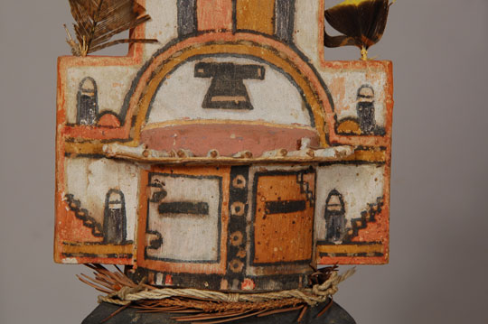 The Hemis Katsina is probably the most beautiful and best known of all Hopi Katsinas. His elaborate headdress, called a tableta, is partly responsible for his beauty. His body is painted with black corn smut with light colored half-moons on the chest and back. He wears a kilt, and around his waist is a Hopi embroidered rain sash.   A fox skin hangs down his back side and is secured by his waist belt.  The tableta is painted with phallic and cloud symbols and capped with feathers.  A reinforcing stick is attached to the mask and tip of the tableta on the rear—something seen in real katsina impersonation but often omitted on dolls. The remnants of an evergreen ruff appear around the neck but it has turned brown over the years and the needles are mostly gone.  Contemporary carvings usually use a green yarn ruff but older dolls such as this one actually used real evergreens.  The sun shade hanging over the eyes of the mask are of the old type where sticks are imbedded into the mask and the shade then attached to the protruding sticks. The arm bands were painted turquoise but most of that natural pigment is missing. This katsina appears in the Home Dance or Niman Ceremony. No other katsinas, neither clowns nor side dancers appear with the line of Hemis except the Hemis Manas.  It is interesting to note that at Hopi, they refer to the Hemis Katsina as having come from the Rio Grande Jemez Pueblo of New Mexico. At Jemez Pueblo, they refer to a similar dance as a Hopi dance. The paint appears to be a mixture of vegetal and mineral, which leads to the determination that the age of the carving is no later than the 1920s. Condition:  The toes of both feet have been repaired but there is no evidence of any other repairs.  The items in both hands are missing.  This is a superb example of a Hemis Katsina. 