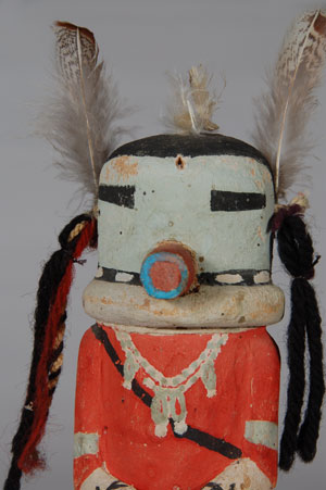 This katsina, sometimes call the Mak Katsina, is considered to be an import from Laguna Pueblo to the Hopi Mesas.  This version is from Second Mesa as defined by wearing a red shirt or red painted body.  This katsina was illustrated by Jesse Walter Fewkes in Plate XLVII of his publication Hopi Kachinas but Fewkes referred to him as “Kwacas Alex Taka,” which translates to “eagle feathers erect man” which is based on the two erect feathers on the head.  Fred Kabotie, famous Hopi artist, illustrated a pair of this katsina in his 1938 watercolor painting “Hunting Dance from Laguna.” The katsina is sometimes referred to at Hopi as a Hunter Katsina.  The katsina doll is painted with blue mineral paint on the face, armbands, skirt hem and moccasins. The white neck ruff and white skirt appear to be mineral paint as well.  The red could be aniline paint.  The katsina doll probably dates to no later than the 1930s.  Condition: The katsina doll is really in excellent condition for a carving of its age.  Provenance: From a private collector  References: Fred Kabotie: Hopi Indian Artist, an autobiography told with Bill Belknap, Museum of Northern Arizona. 1977. Kachinas: A Hopi Artist’s Documentary by Barton Wright, Northland Press, 1973. 