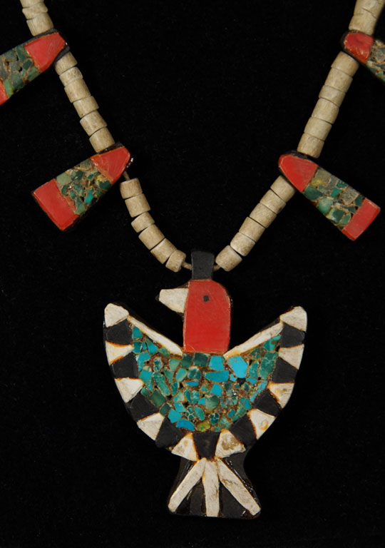 During the 1930s when the Depression-era was in full swing, New Mexico Pueblo Indians were severely affected. At Santo Domingo Pueblo (now Kewa Pueblo), the Indians became very resourceful and began producing jewelry from whatever material they could find. One particular folk art creation they produced has become a very collectible item: the Depression-era necklace.  Production continued at a lesser rate into the mid-20th century.  This necklace was made from several “found materials.” The beads were made from bone, the black backing probably from automotive battery boxes, the red from toothbrush handles or something similar, and the turquoise is genuine. These necklaces were usually in the squash blossom style, with pendants protruding from the sides and a bird pendant at the bottom, as is this one.  When we acquired this one, it came with two triangular shaped pendants that could easily be converted to earrings.  They are included with the purchase of the necklace.  Condition:  It is in very good condition. Provenance: from a Santa Fe resident Recommended Exhibit:  A current exhibit of an extremely large quantity of these necklaces is at the Wheelwright Museum in Santa Fe.  It is highly recommended as a source to learn more about this wonderful period of pueblo ingenuity. Recommended Reading: Santo Domingo Pueblo Jewelry by Sally and J. Roderick Moore in The Magazine Antiques, Brant Publications, Inc. July 2009, vol. CLXXVI, no. 1. pp. 56-61. 