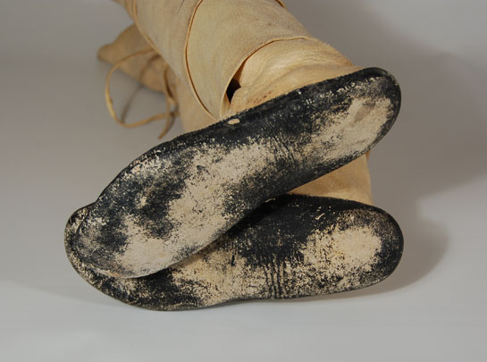 Pueblo women wear white buckskin moccasins with hard soles and soft deerskin uppers.  The soles are cut from rawhide or the tanned, thick, neck skin of the deer, which is exceptionally strong and heavy.  The white leggings are made from soft deerskin and attached to the moccasins and then wrapped around the woman’s legs in overlapping rows until they reach just below the knee.  Condition:  the moccasins are in exceptional condition and evidence wear to the black soles demonstrating their use in dances.  Provenance: from the estate of a native of Kewa Pueblo  Recommended Reading: Ceremonial Costumes of the Pueblo Indians: Their Evolution, Fabrication, and Significance in the Prayer Drama by Virginia More Roediger 