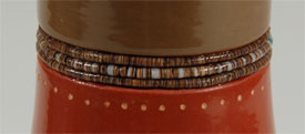The upper part of the neck of the jar is slipped in green clay.  The green and red slips are separated by three rows of very fine hieshe imbedded into the clay.  
