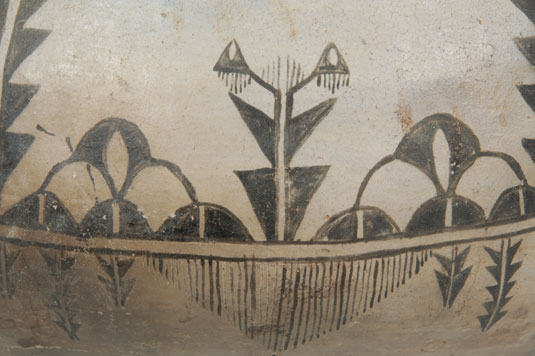 This vessel is somewhat primitive in construction.  It was constructed using coils of clay, as is traditional, and some of the coils are visible as waves on the vessel wall.  Apparently the wall was not sanded in the manner potters of today do.  The vessel is profusely illustrated with clouds, rain, lightning and plants.  The neck of the vessel is vertical in the style of prehistoric Biscuit Ware, a style not generally associated with Keres Pueblos.  The jar is intriguing in its unusual shape and surface finish.  It is quite likely from the 1880s.