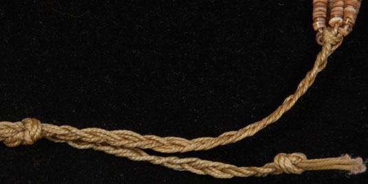 The 5 strands are secured together with woven waxed string strung together and secured at the ends.