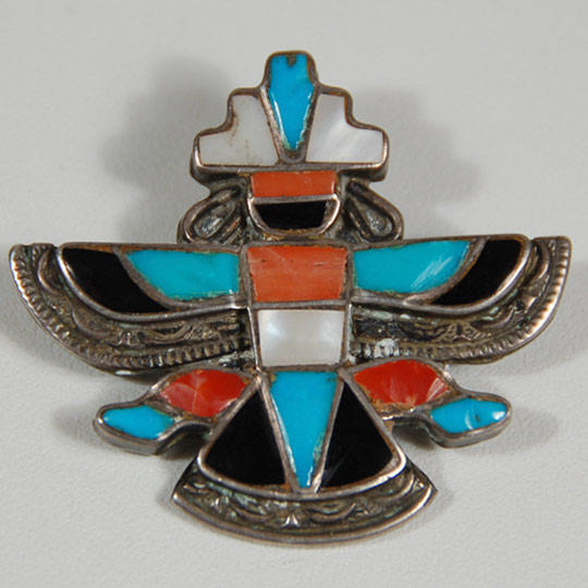 This channel-inlay pin consists of turquoise, jet, mother-of-pearl, and Spondylus shell, mounted in silver bezels on silver backing. Silver wire earrings and a "halo" around the wing and tail feathers complete the ensemble.  The pin probably dates to the second half of the 20th century.  The pin clasp has a safety hook.  It is not signed with the name of the maker.   Condition: as new Provenance: from a gentleman in Santa Fe Recommended Reading: Zuni Jewelry by Theda and Michael Bassman