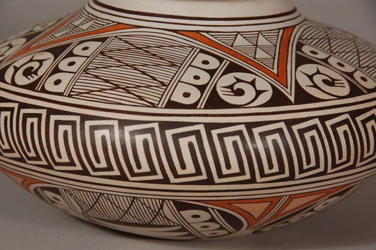 Burel Naha is the son of Helen Naha (Feather Woman) and brother of Rainy Naha and Sylvia Naha.  Burel and his sisters have continued the tradition of their famous mother in producing pottery of the finest quality and with superb design creations.  This outstanding seed jar is magnificent whether viewing it from the top down, from the side, or even from the bottom up.  The artist spared no effort to make it a visual treat.  Every square inch is covered in exquisitely applied elements.  It is signed with the artist’s hallmark Long Hair Katsina image.  Condition:  the jar is in original condition  Provenance:  from an Albuquerque gentleman 