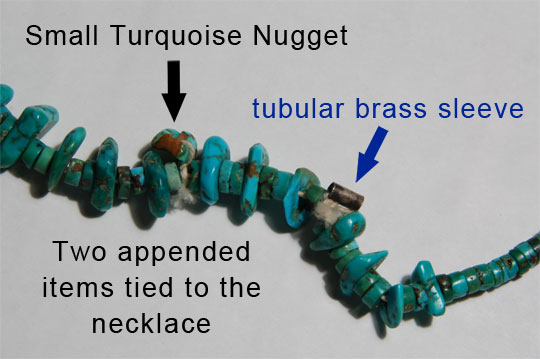 Near the top of the necklace are two appended items tied to the necklace.  One is a tubular brass sleeve and the other is a small turquoise nugget.  This is a standard practice on necklaces made for Native use and never seen on necklaces made for sale.