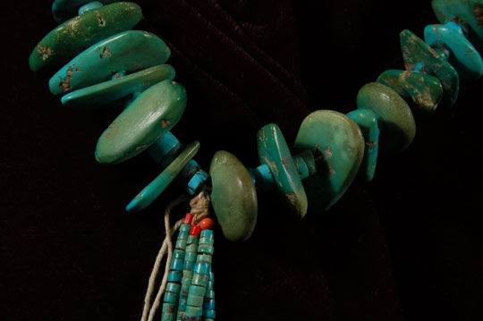 This is an exquisite Navajo turquoise nugget necklace comprised of beautiful dark blue and dark green off-center drilled turquoise stones and turquoise hieshe with a pair of jaclas. The turquoise hieshe is all hand-cut and hand-drilled. Some of the nugget turquoise stones are drilled off center, which is a favorite manner for pieces made for Native use. The turquoise is all-natural and untreated.  Near the top of the necklace are two appended items tied to the necklace.  One is a tubular brass sleeve and the other is a small turquoise nugget.  This is a standard practice on necklaces made for Native use and never seen on necklaces made for sale. This is a style necklace favored by Navajo and Pueblo natives and is often seen in historic photographs of both tribes. This particular necklace was most likely made and worn by a Navajo and eventually pawned at the trading post and surrendered. It has not been restrung and is as pawned by the owner.  Turquoise has always had enormous sacred and economic value among Southwestern cultures.  In prehistoric times, a lively turquoise trade network extended from the West Indies and the Yucatán Peninsula to the Southwest and from California to Mississippi.  Ancient turquoise offerings were found by archaeologists under support posts and in sealed wall crypts in the kivas of Chaco Canyon in New Mexico.  (Dubin) Necklaces of this style long preceded silver and turquoise necklaces seen today.  The Navajo and Pueblo natives wore these as standard items of jewelry long before the advent of silver in their lives.  There are no necklaces more traditional than these. Condition: The necklace is in excellent condition. Provenance: from a gentleman in Florida Recommended Reading: North American Indian Jewelry and Adornment by Lois Sherr Dubin 