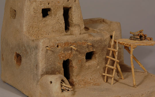 Many potters who maintained tradition in production of pottery occasionally found time or the inclination to make a tourist item that was guaranteed a fast sell.  Miniature pueblo houses were items that were of interest to travelers to the pueblos who were seeking a souvenir to remind them of their visit.  This two-story house of micaceous clay was probably made at Taos Pueblo in the mid-20th century.  The structure is made of micaceous clay and wood sticks used to simulate firewood, vigas, ladder, etc.    Condition:  overall condition is very good.  A few minor chips in the clay and a few missing wood sticks are evident but not distracting.  Because of the delicate nature of the wood pieces, we do not feel comfortable shipping this item.  The purchaser will have to arrange to pick it up in person.  Provenance: from the collection of Katherine H. Rust  Recommended Reading:  Pottery of the Southwest: Ancient Art and Modern Traditions by Allan and Carol Hayes 