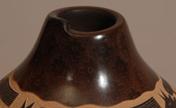Jody Naranjo is a prize-winning potter from Santa Clara Pueblo who has taken the art form of pueblo pottery to a brand new level. She has been awarded prizes since she was a teen.  She comes from a family of prize-winning potters and artists.   While continuing the tradition of hand coiling and hand polishing pottery as done by her ancestors she brings a totally contemporary vibrancy to her work.  She began making pottery with her grandmother, Rose Naranjo, when she was eight years old. By the time she was a teenager she was creating prize-winning works of art.  Jody is an artist who weaves tradition and innovation in a most delightful way.  This little jar is a perfect example of her artistic talent. It incorporates the traditional method of hand coiling native clay and hand burnishing with a unique method of sgraffito to create a panoramic design of Indians on horses which she has named &ldquo;Crazy Horse.&rdquo;  It is difficult to see in these photographs, but around the neck and base of the jar, the artist has inscribed designs that literally appear to be under the surface of the clay.    Condition: original condition  Provenance: from an Albuquerque gentleman  Recommended Reading: Pueblo Indian Pottery: 750 Artist Biographies by Gregory Schaaf 