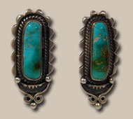 This pair of earrings appears to be from the last half of the 20th century.  Each is stamped with a capital R enclosed by a capital D.  I have not yet determined to whom those initials belong.  A long oval and domed beautiful blue turquoise stone with golden copper matrix is set in a silver bezel that is mounted on silver stock scalloped on its edges.  Twisted silver rope encircles the stone.  The earrings are for pierced ears.   Condition: original condition   Provenance: from the collection of a Santa Fe resident