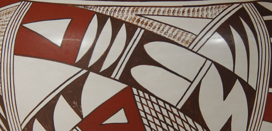 Joy Navasie is among the most famous of Hopi-Tewa potters. She learned the skill from her famous mother, Paqua Naha, the first Frog Woman. Naha developed white ware pottery in the mid-1950s and Navasie picked up the tradition and continued it until her retirement in 1995. Her daughters have now continued the tradition.  This jar is beautifully decorated with stylized birds and feathers in true Hopi fashion. The dark brick red and strong black paints stand out beautifully against the pure white slip.  The jar is signed on the bottom with the traditional frog hallmark of Joy Navasie.  Condition: The jar is in original excellent condition.  Provenance:  from an Albuquerque gentleman  Recommended Reading: Fourteen Families in Pueblo Pottery by Rick Dillingham 