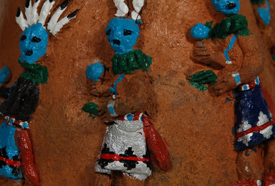 Silas and Bertha Claw broke with Navajo pottery tradition and the customs of their fellow tradesmen.  Their forms remained true to tradition but they used an appliqué technique for design elements and colorful oil or acrylic paints for highlights.  They were of the Shonto/Cow Springs region of the Navajo Reservation.  Silas passed away in 2002 but we have found no record of Bertha passing away.   Around 1968, Silas began working in clay even though pottery making, like basket making, was considered women's work.  Bertha assisted him from the very beginning.  The Claws made a variety of pottery shapes: traditional-style cooking jars, wedding vases, triple-spouted jars, and ceramic beads.  It is not known which one did which part of the production but it is believed Bertha would form the vessels and Silas would decorate them with a variety of appliquéd and incised plant and animal motifs—usually in high relief and occasionally in full round. These motifs depicted a wide range of subjects that included cactus plants and blooming yuccas, oak leaves with acorns, ears of corn, a menagerie of domestic animals, and horned toads. Silas often applied oil paint in a range of colors to portions of the appliqué to make them even more realistic. He then would coat the vessel with varnish.   This wedding vessel shows a procession of Navajo Yei dancers executed in appliqué on the body of the vessel. On the other side of the vessel is a Navajo hogan with smoke from the chimney.  The wedding vessel is an older one by this couple and is signed S.B. Claw on the underside.   Condition: original condition Provenance: from the John Barry collection of California Recommended Reading: - Navajo Folk Art: The People Speak by Chuck and Jan Rosenak. - "The Navajo Pottery of Silas and Bertha Claw" by Ed Dobbins and Scott C. Russell, American Indian Art Magazine, Spring 2007. Vol. 32, No. 2.