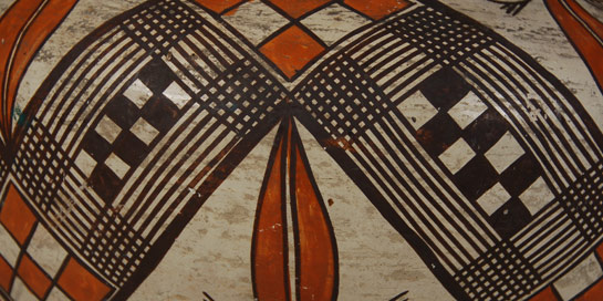 This is most likely a Laguna Pueblo polychrome olla that is truly an exceptional work of art. This exemplary olla dates to circa 1920, and is a superb example of the potter's art.  The design field is broken into three horizontal sections, which perfectly accentuate and compliment the form of the jar. The upper band, below rim top, extends to the upper shoulder, with parallelogram bars and floral elements with berries.  The middle design is a continuous bold wide zigzag band that is the focal design element of the vessel. It is filled with black checkerboard, orange checkerboard and overlapping fine line elements.  The lower band of design is similar to the upper band but on a larger and bolder scale.  The underbody is orange. Double framing lines between the design and underbody do not have ceremonial line breaks. The jar has a concave base, brown rim and orange painted on the inside lip to a depth of about 3 inches. There is a slight tilt to the posture of the jar.  This work is perfectly typical of Laguna ceramics, in form, construction, materials, and design execution. The parallelogram bars are very typical of Laguna Pueblo design elements, as are the plants with berries. The plants with berries are a feature taken by Laguna potters to Isleta Pueblo when they migrated there in 1879.  This jar is marvelously patinated, with a smooth, semi-gloss sheen; a complexity of depth, color, and surface completely unattainable save through the intricacies and subtleties of an aged surface, evidence of many years of service within the pueblo.   Condition: the jar is in very good condition with wear expected on a jar of this age. The owner stated that a small rim chip was repaired but there is no clear evidence of that through UV examination. Provenance: from the collection of a Santa Fe resident. Recommended Reading:  Acoma and Laguna Pottery by Rick Dillingham 