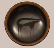 Tony Da, from San Ildefosno Pueblo, was destined to become one of the finest artists of the 20th century. His grandparents, Maria and Julian Martinez, and his father, Popovi Da, were skilled artists. Tony was a painter from early in life, and was winning awards for his paintings. A change occurred when he moved in with his grandmother in 1966. She taught him the techniques of pottery making and he learned very well. Within three years, Maria said he had nothing else to learn from her.   Once Tony started making pottery, his creativity blossomed. He followed all the traditional techniques Maria had taught him, but he matured as an artist in departing from traditional shapes and designs. He was fond of the Mimbres culture and used its designs on much of his work.   Tony's first pottery pieces were bears. Maria commented that he was very good and she could not do anything to make him better, except that he needed to learn to make ollas, which, of course, he did. In 1982, Tony suffered massive head injuries in a motorcycle accident, which left him unable to continue his pottery career.  Fortunately for us, he left a legacy of outstanding art objects.   This black and sienna plate is a truly breathtaking and superlative design, with a Mimbres-style deer boldly placed in the center. It is a masterpiece of design and execution, a piece worthy of the Da name. Coil formed in native San Ildefonso clays, slipped, and stone-polished to a surface of the utmost quality, this plate was then fired in a non-oxidation firing to achieve the lovely deep black coloration. The sienna rim and sgraffito design were achieved after the firing, utilizing the sharpest attention to detail and superb technical ability to create motif and patterning of such intricacy, delicacy, and great beauty.  Condition:  in superb original condition and signed on the underside with his hallmark. It was probably made in the 1970s. Provenance: from the estate of Michael Frost Recommended Reading:  The Life and Art of Tony Da by Charles King and Richard Spivey