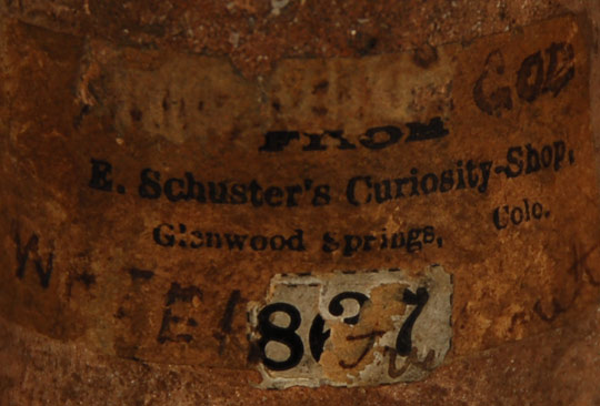 There is a label on the back of the figurine which reads From E. Schuster’s Curiosity Shop, Glenwood Springs, Colo.