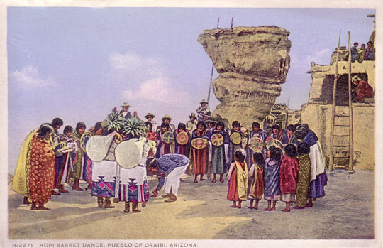 The postcard shown in the image on this page presents a good example of an actual basket dance at the village of Oraibi on the Hopi Reservation.  Although not dated, the post card was probably made around 1900.  We will include the post card with the purchase of the painting.
