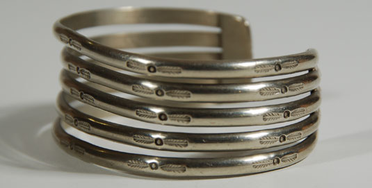 five domed and stamped silver strips separated at the top and anchored at the ends with a silver bar