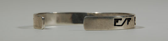 This bracelet is typical of the Hopi overlay silverwork.  A design if cut into a silver strip using a jeweler’s saw and then that strip is laid over another silver strip which has been oxidized.  Once finished, the two silver strips result in a Hopi overlay bracelet.