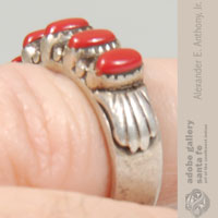 A sea shell design overlays the silver band at the ends of the row of coral cabs.  