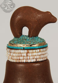 The jar is topped with a precisely fashioned stopper on which bands of white shell heishi, turquoise heishi and ground turquoise form a platform for a two-inch brown bear. The bear is a symbol of healing to many Southwestern tribes. 