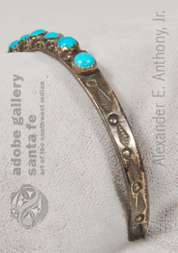 On a sterling silver band - small drops of silver line the edges and the sides are stamped with feather designs. It dates from the mid-20th Century.