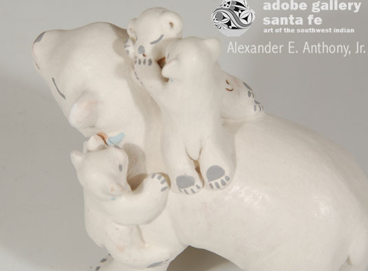 This polar bear has her eyes closed and what appears as a smile as she entertains her cubs by letting them climb all over her.  The two on her back are playing and a third one is climbing up her side.