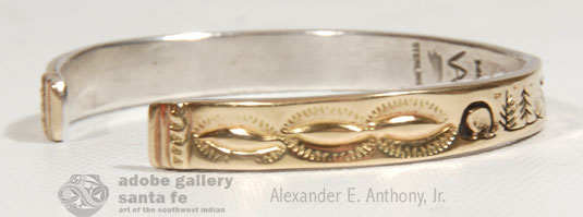 This Vidal Aragon storyteller bracelet consists of two layers. The top layer is 14K gold into which the artist precisely cut designs of three animals—a deer, a wolf and a bear. The animals wander through a desert landscape with pine trees and sage. At one point there is water and what seems to be birds flying overhead. The gold layer is then placed over silver and the silver is oxidized to create a striking contrast between the gold and silver.