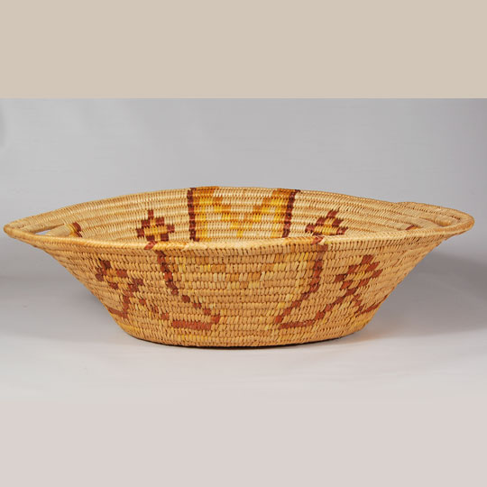 Jicarilla Apache basketry covers a long span of time, but very little is known of their work before they were settled on a reservation in 1887 in northern New Mexico. All Jicarilla baskets are of coil weave, usually of sumac, but sometimes of willow.  The Jicarilla Apache women generally made large deep basket bowls for winnowing or storage.  They were designed with elements of commercial dyes, so fading is quite normal on a basket of some age.   The Jicarilla Apache Nation is located in the mountains and rugged mesas of northern New Mexico.  The landscape offers diverse scenery of Ponderosa pine forests in mountainous terrain and Piñon pine mesas with sage brush flats.  Dulce, New Mexico, is the Jicarilla Apache Nation Headquarters.   This basket is typical of the style made for sale to collectors and visitors to the Jicarilla village.  It is oval shape and the outer two rows at the top of the basket were extended to form handles at the two ends.  The edge of the rim was finished in a herringbone weave. Condition:  Very good condition Provenance: from the collection of Katherine H. Rust Recommended Reading:  Southwestern Indian Baskets: Their History and Their Makers by Andrew Hunter Whiteford