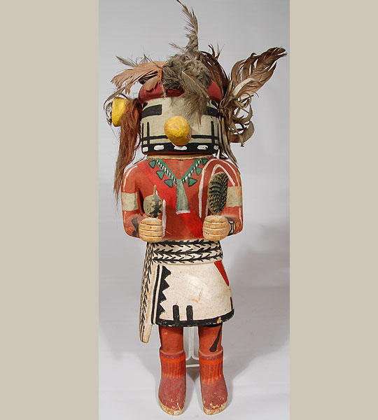 This is an exceptional Hopi Tasap Katsina doll carved from a piece of cottonwood root. Tasap is a Hopi representation of a Navajo God. There are Hopi versions of katsinam that honor and depict other tribes, such as the Navajo, Havasupai, Comanche, Zuni and other Pueblos. This is the Hopi version of what the Navajo katsinam might look like. These katsinam are not borrowed from the Navajo, as they are unique to the Hopi. They have the same purpose and functions as all the Hopi Katsinam. They are messengers and/or intermediaries to the rain gods. Since they are katsinam in every respect, they are afforded the same reverence and dignity during their visits. This Tasap male katsinam wears a ceremonial kilt and rain sash, and has a blue face and red hair. The male, along with a companion female, appears during Angak'wa and the summer katsina day dances. Since they depict the Navajo, their songs may have some Navajo words speaking of the good things of life and/or words representing moisture. Condition: The carving is in excellent condition. Provenance: To be provided to purchaser